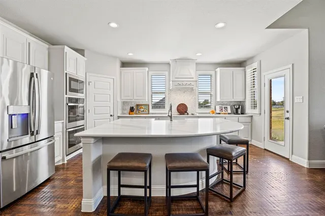 a kitchen with stainless steel appliances a table chairs refrigerator and microwave