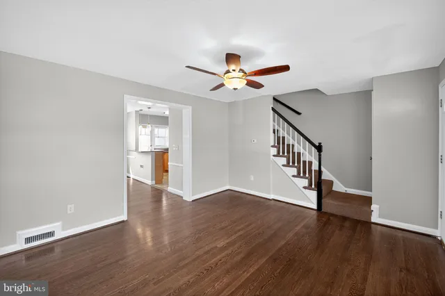 a view of an empty room with wooden floor and a ceiling fan