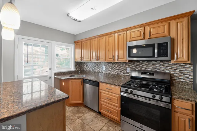 a kitchen with granite countertop a stove sink and microwave
