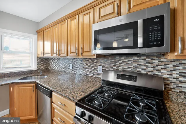 a kitchen with granite countertop a stove sink and microwave