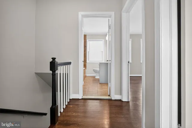 a view of a hallway with wooden floor and a bathroom