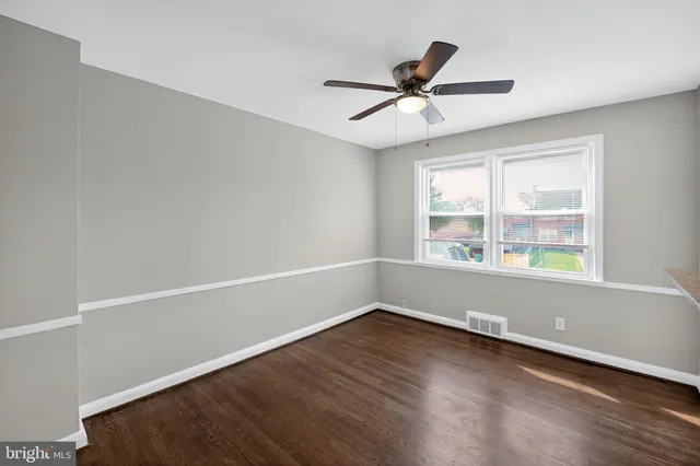 an empty room with wooden floor fan and windows