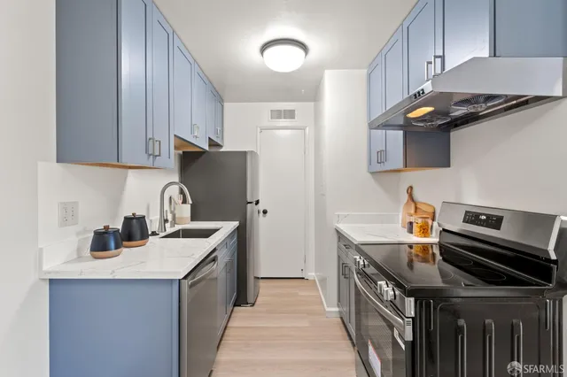 a kitchen with stainless steel appliances granite countertop a sink a stove and a refrigerator