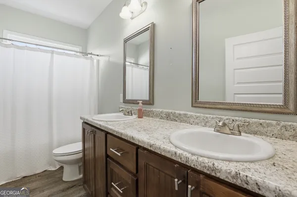 a bathroom with a granite countertop sink a toilet and a mirror