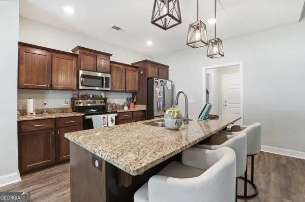 a kitchen with stainless steel appliances granite countertop a sink a stove and chairs
