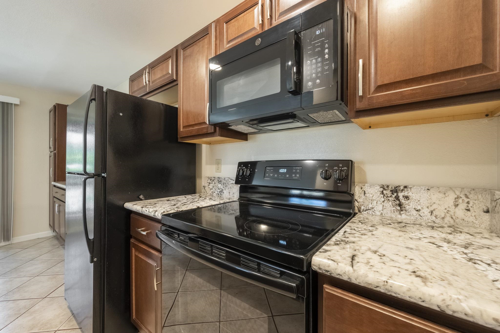 480 Kenolio Road, Unit 31205 Kihei, HI 96753 - Photo 15 of 45 a kitchen with stainless steel appliances granite countertop a stove microwave and refrigerator