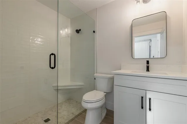 a bathroom with a toilet sink vanity and shower