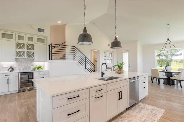 a kitchen with kitchen island granite countertop a stove a sink a dining table and chairs with wooden floor