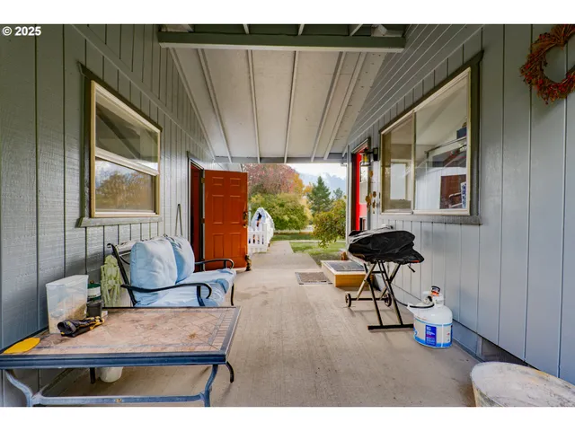 a backyard of a house with table and chairs plants and large trees