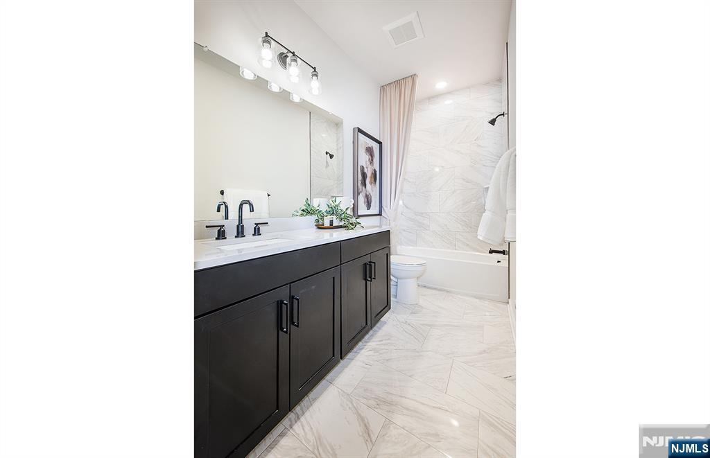 400 Sycamore Street, Unit 405 Kearny, NJ 07032 - Photo 11 of 28 a spacious bathroom with a double vanity sink a mirror and a bathtub