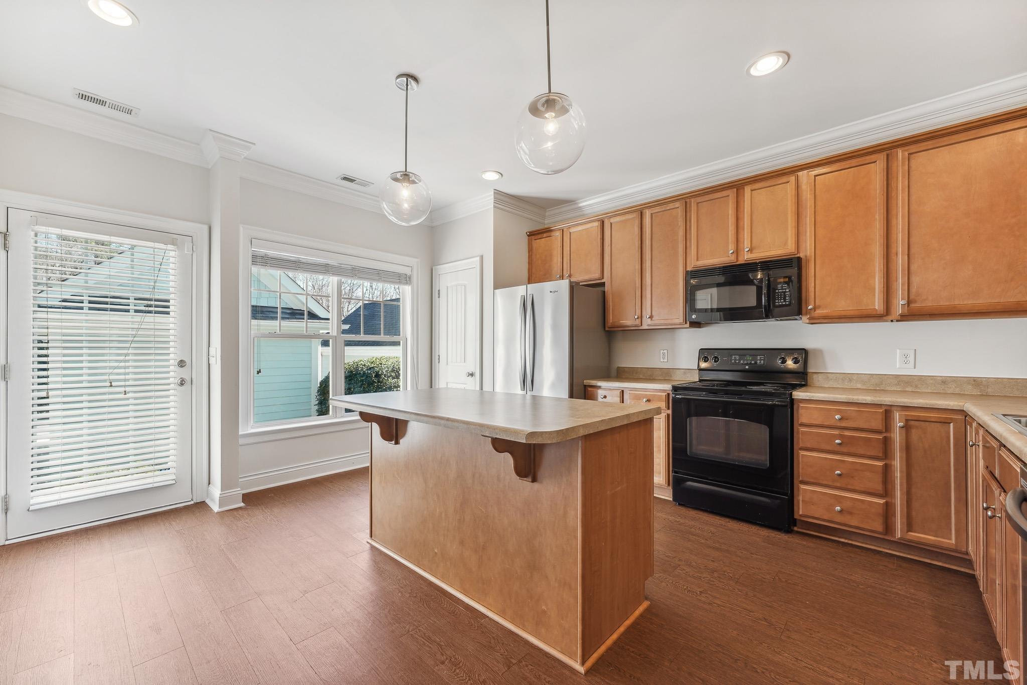 7710 ACC Boulevard Raleigh, NC 27617 - Photo 12 of 33 a kitchen with kitchen island granite countertop a stove top oven a sink dishwasher a dining table and chairs with wooden floor
