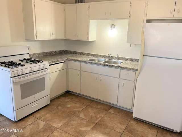 a kitchen with sink cabinets and white appliances