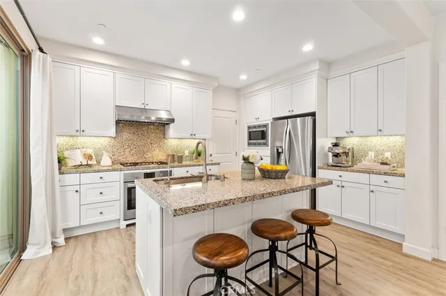 a kitchen with granite countertop white cabinets and stainless steel appliances