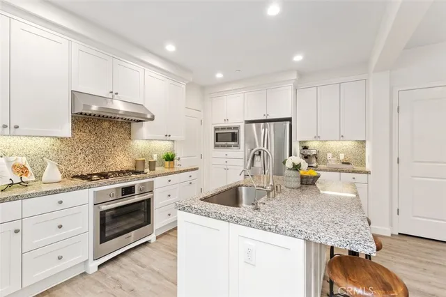 a kitchen with stainless steel appliances granite countertop a stove sink and cabinets