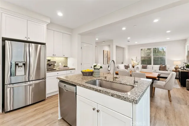 a kitchen with granite countertop a refrigerator a sink a stove a dining table and chairs