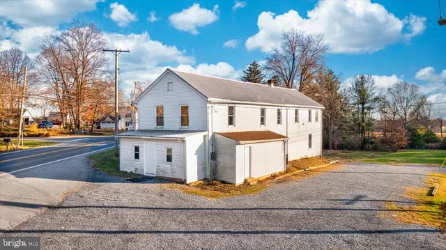 a view of a white house with a yard next to a road
