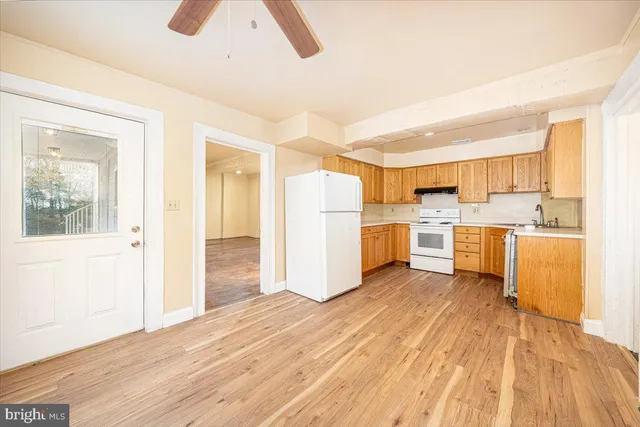 a kitchen with stainless steel appliances granite countertop a stove a sink and white cabinets with wooden floor