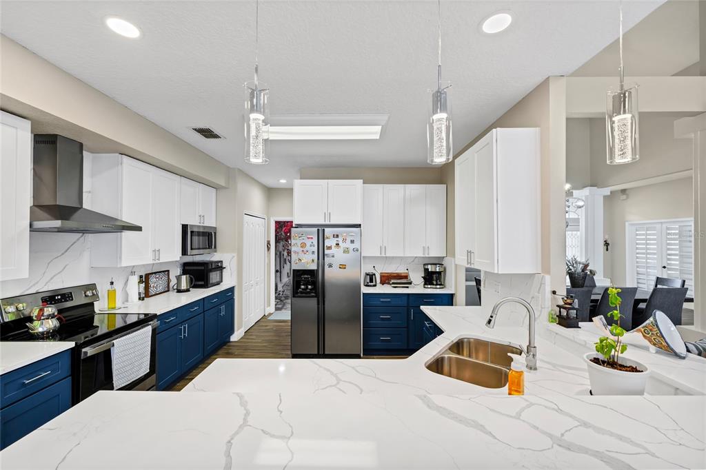 841 Grovesmere Loop Ocoee, FL 34761 - Photo 12 of 48 a kitchen with stainless steel appliances kitchen island granite countertop a sink dishwasher stove and white cabinets with wooden floor