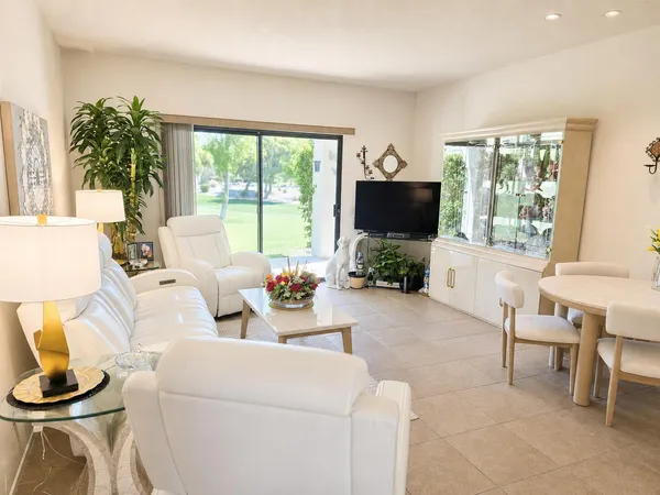 a living room with furniture a flat screen tv and a large window