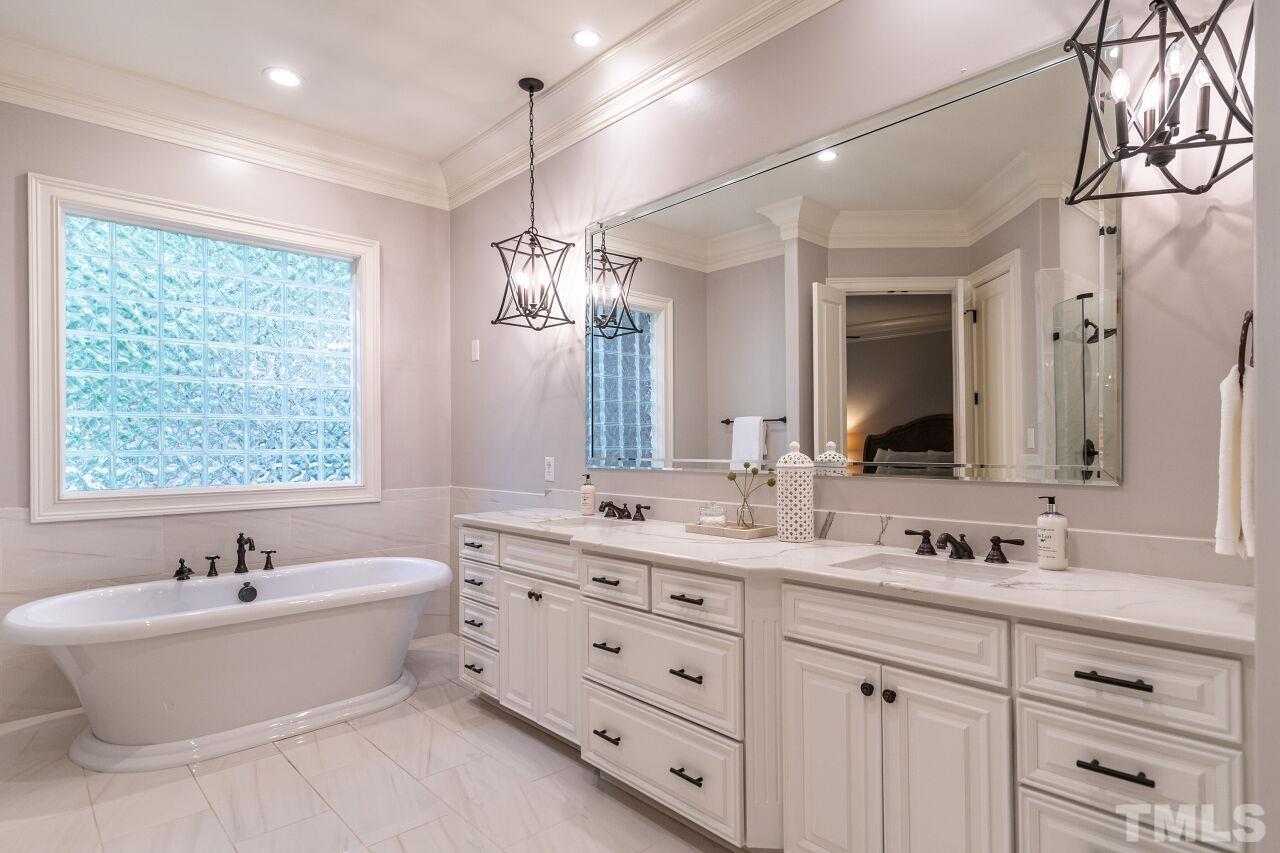 1715 Nottingham Road Raleigh, NC 27607 - Photo 18 of 35 a bathroom with a double vanity sink large mirror and a bathtub