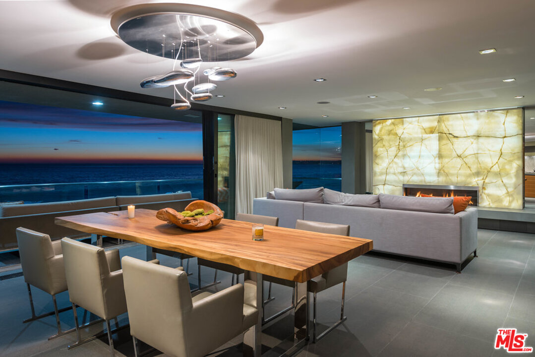 24450 Malibu Road Malibu, CA 90265 - Photo 22 of 34 a dining room with furniture a chandelier and a large window