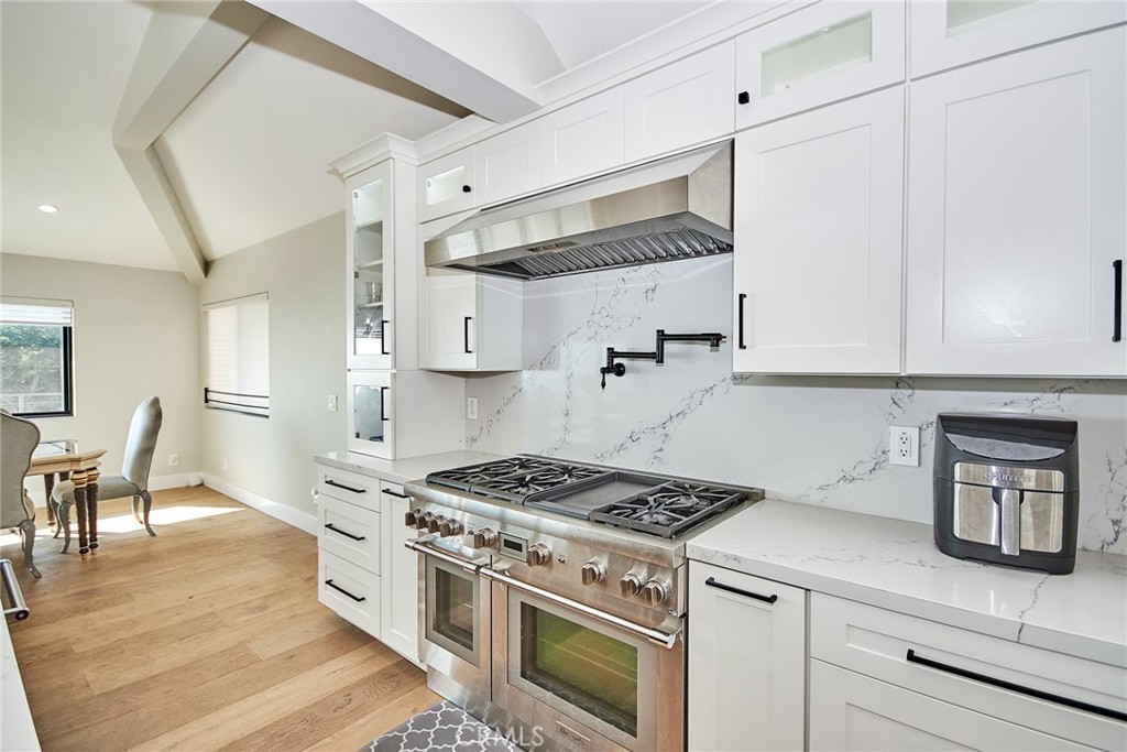 243 Notteargenta Road Pacific Palisades, CA 90272 - Photo 22 of 56 a kitchen with stainless steel appliances granite countertop a stove and white cabinets