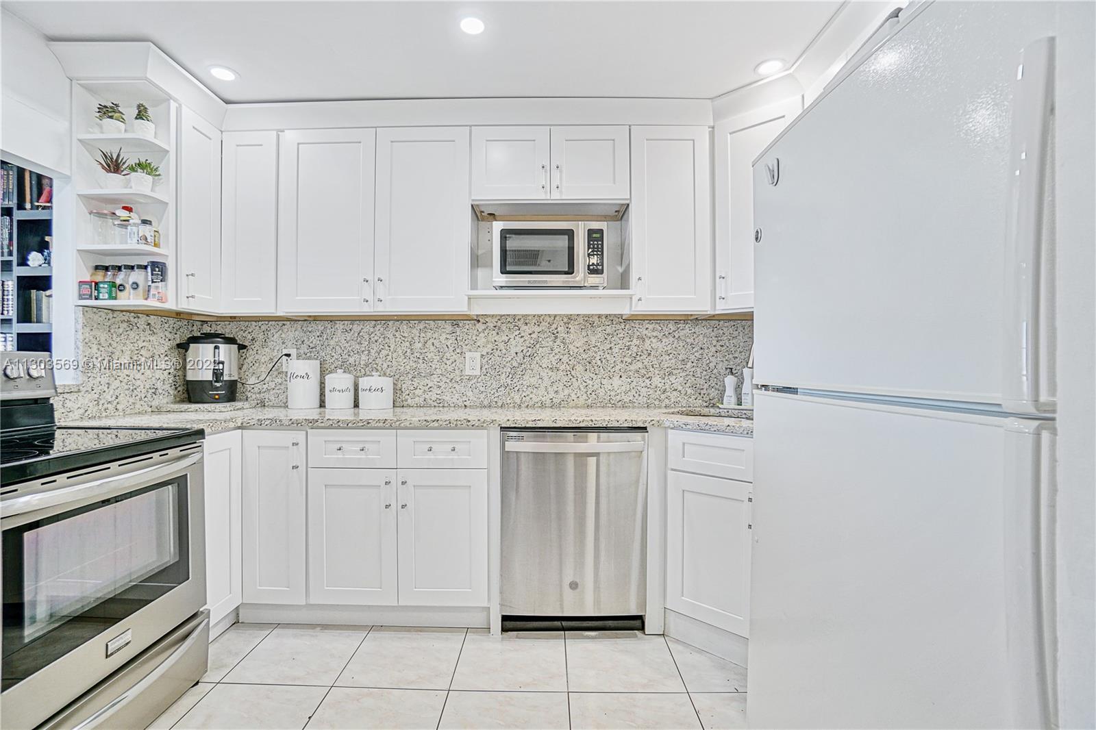4101 Pine Tree Drive, Unit 908 Miami Beach, FL 33140 - Photo 15 of 41 a kitchen with white cabinets and white appliances