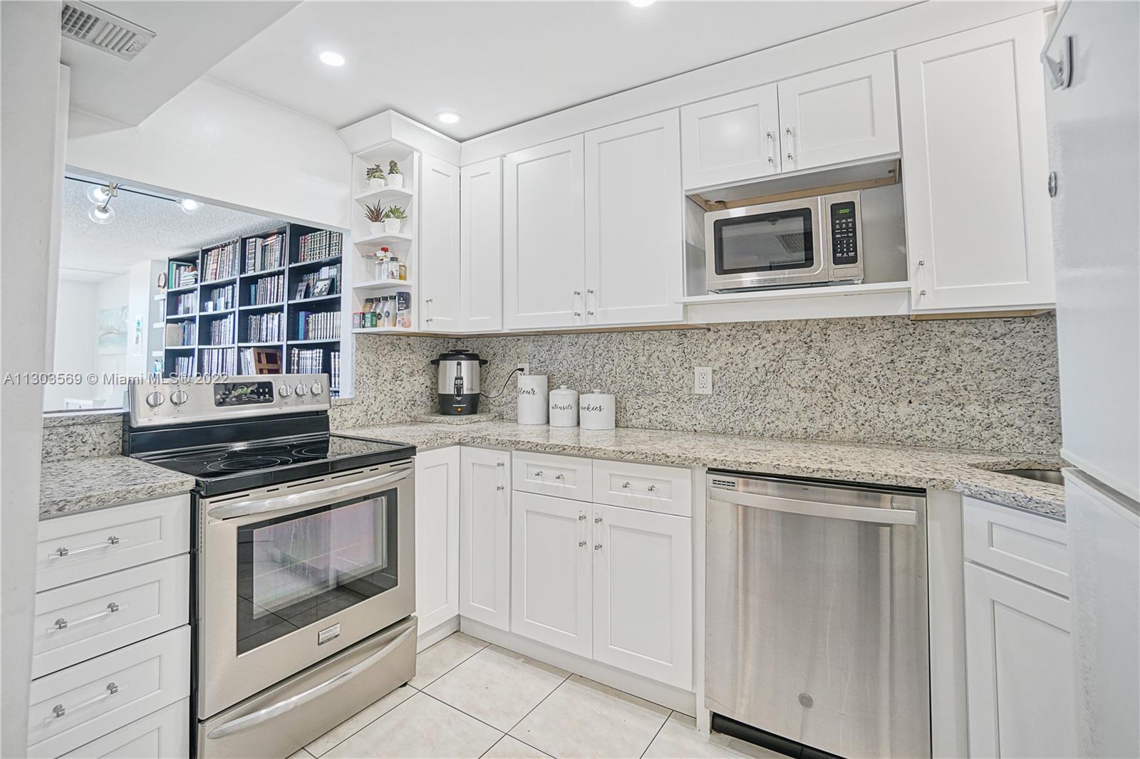 4101 Pine Tree Drive, Unit 908 Miami Beach, FL 33140 - Photo 16 of 41 a kitchen with white cabinets and appliances
