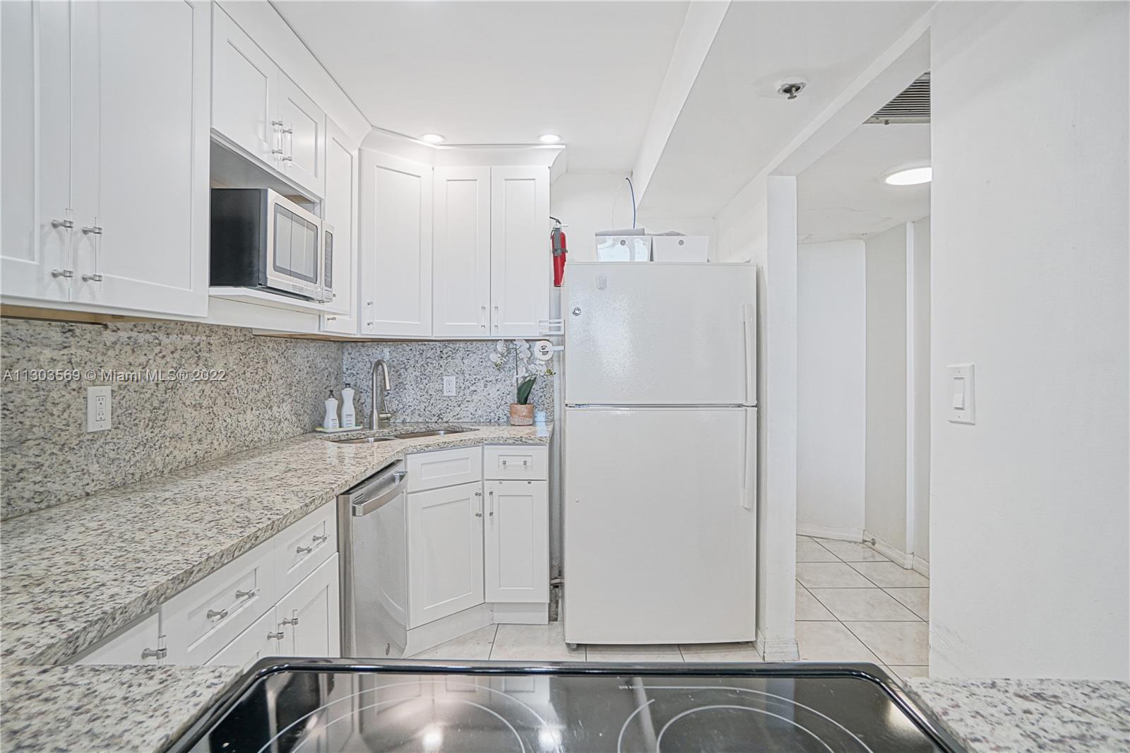 4101 Pine Tree Drive, Unit 908 Miami Beach, FL 33140 - Photo 17 of 41 a white refrigerator freezer sitting inside of a kitchen