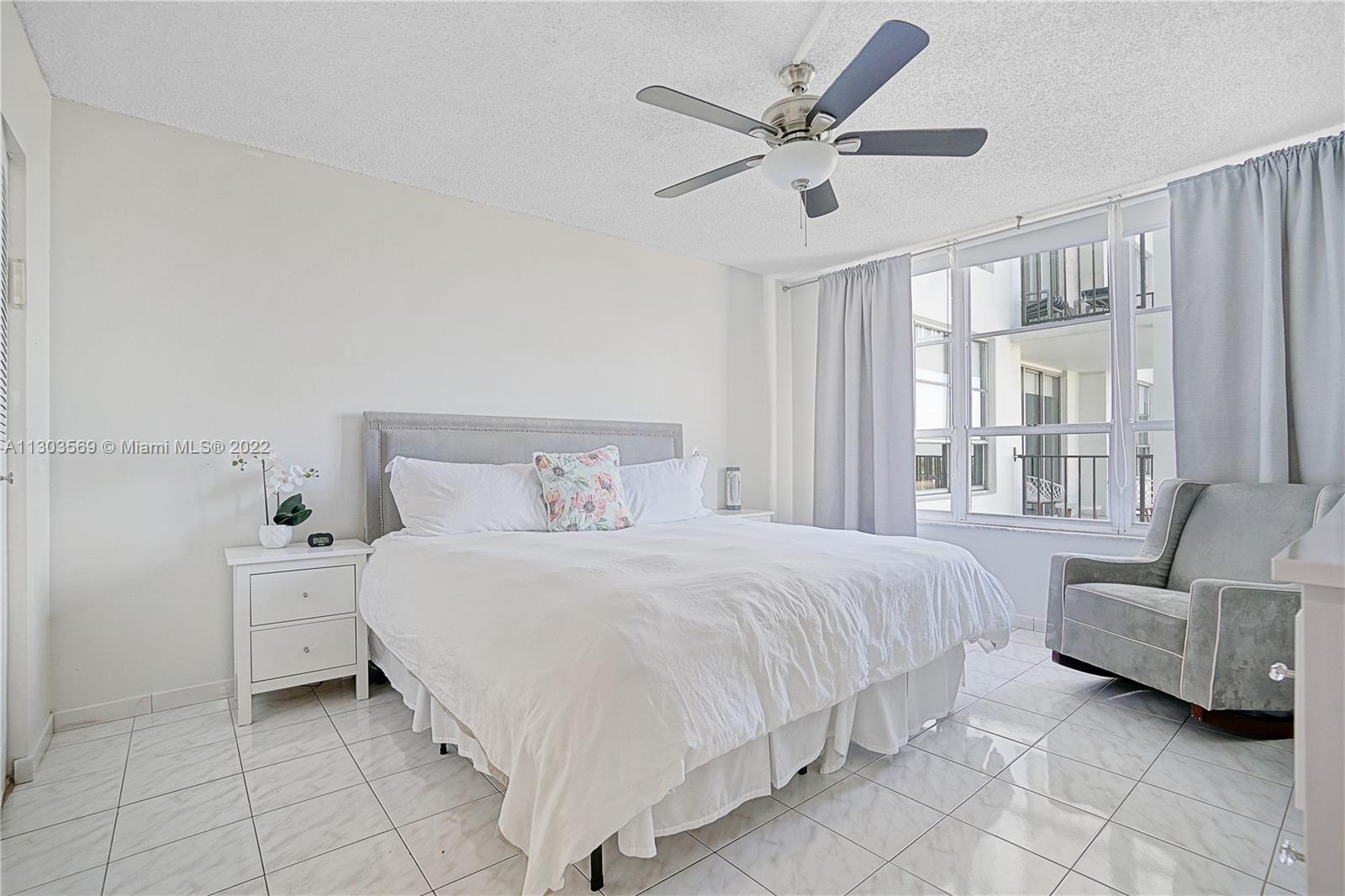 4101 Pine Tree Drive, Unit 908 Miami Beach, FL 33140 - Photo 19 of 41 a bedroom with a bed a couch and a large window