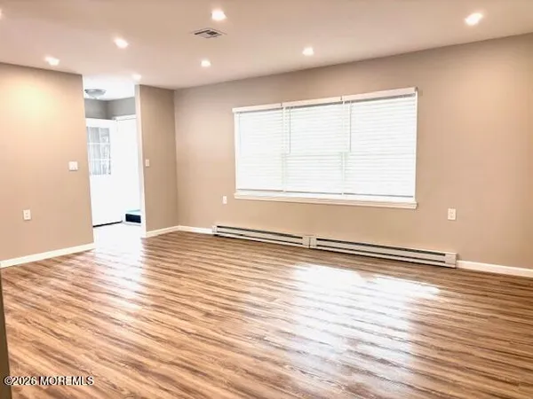 an empty room with wooden floor and windows