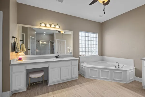 a spacious bathroom with a tub sink and mirror