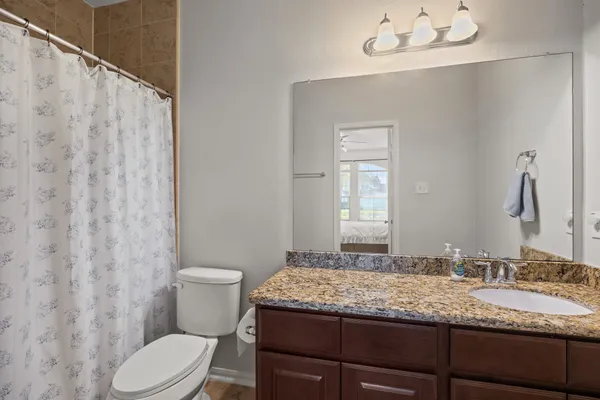 a bathroom with a granite countertop sink toilet and mirror