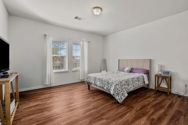 a bedroom with a bed wooden floor and a flat tv screen on a dresser