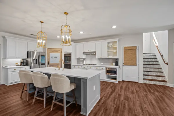 a kitchen with stainless steel appliances a dining table chairs stove and white cabinets