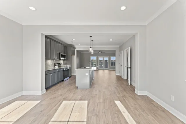 a dining hall with stainless steel appliances granite countertop a refrigerator oven a sink dishwasher and white cabinets with wooden floor