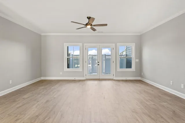 a view of an empty room with a window and wooden floor
