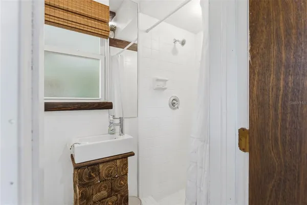 a bedroom with a bed a large window and wooden floor