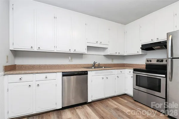 a kitchen with granite countertop white cabinets and stainless steel appliances