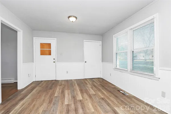 a view of empty room with wooden floor and windows