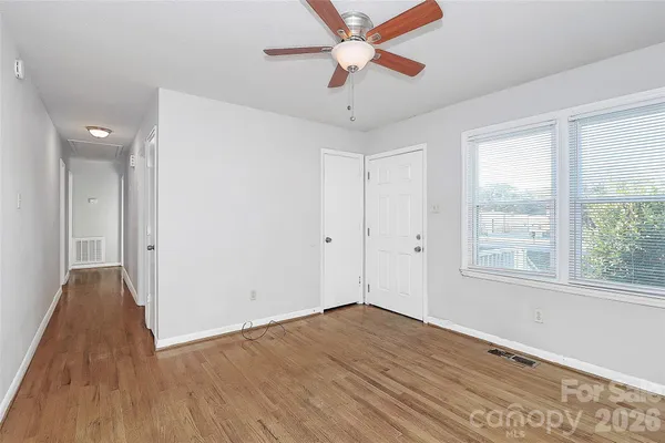a view of empty room with wooden floor and fan