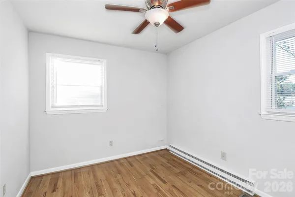 an empty room with a window and a fan