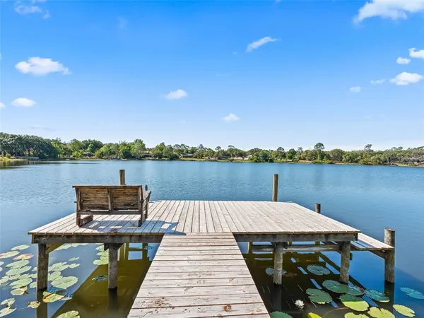a wooden bench sitting on top of a lake next to a yard