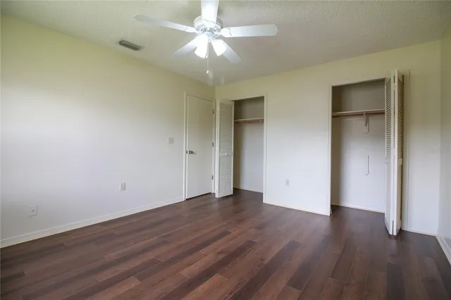 an empty room with wooden floor and a ceiling fan
