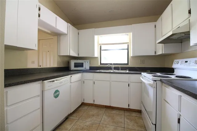 a kitchen with granite countertop white cabinets sink and white appliances