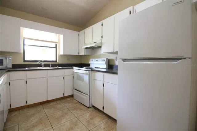 a kitchen with white cabinets and white appliances