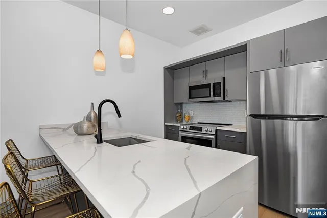 a kitchen with stainless steel appliances kitchen island a refrigerator and a stove top oven