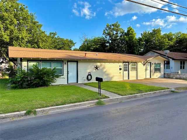 a view of a house with a big yard and potted plants
