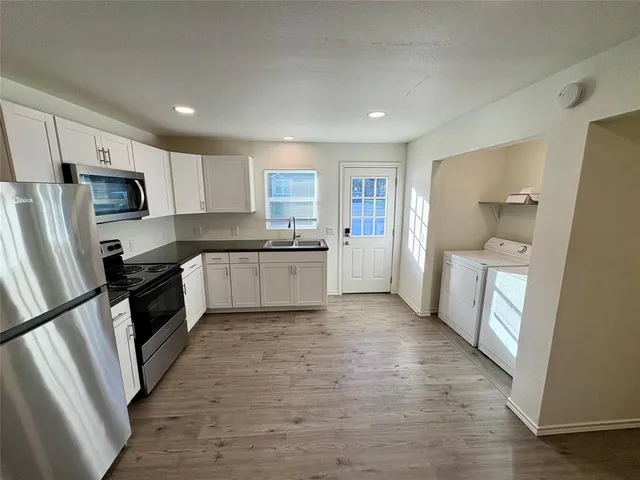 a large kitchen with a refrigerator a sink a stove a microwave and cabinets