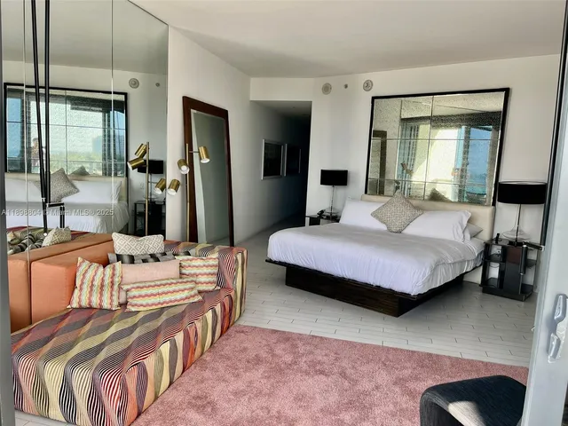 a bedroom with a bed a table and large mirror